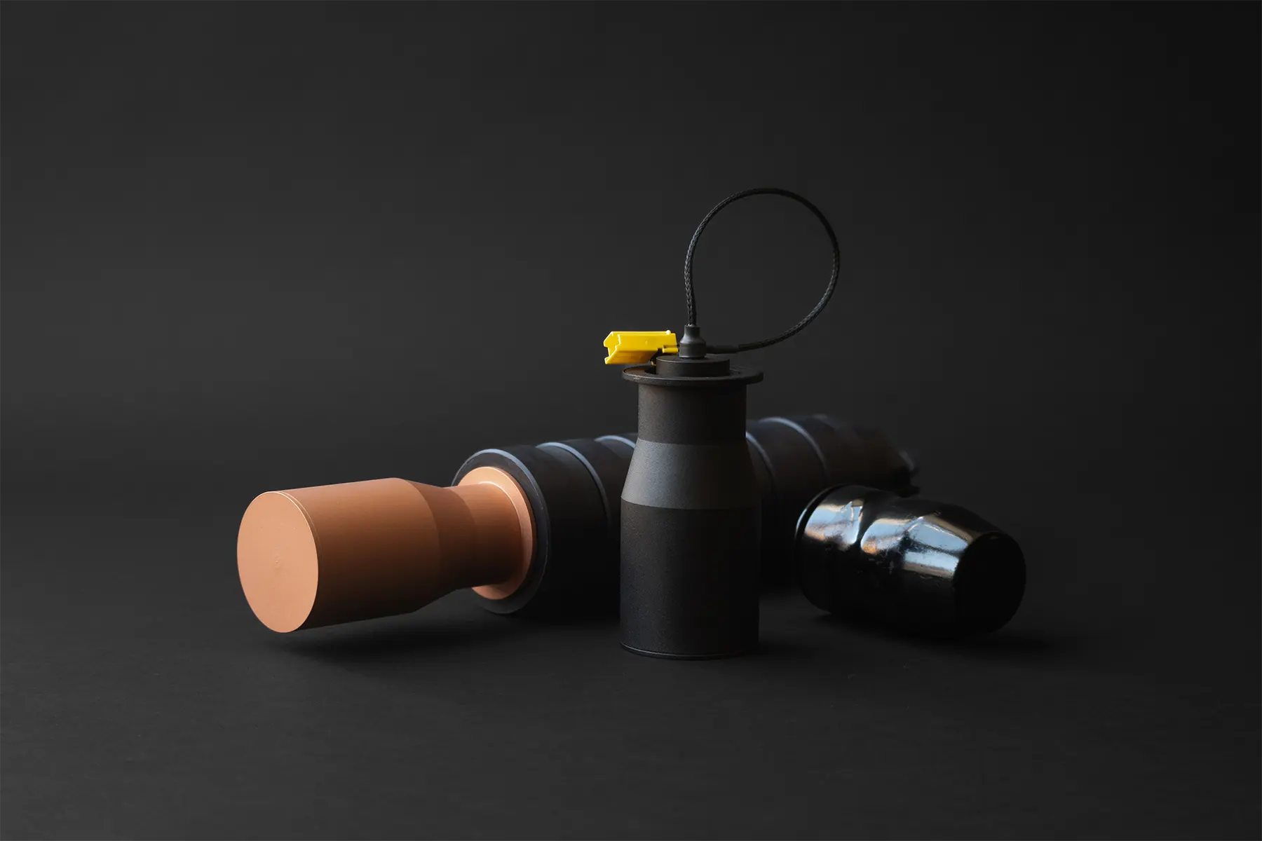 Drone warheads with modular black bodies and yellow safety plugs on dark background