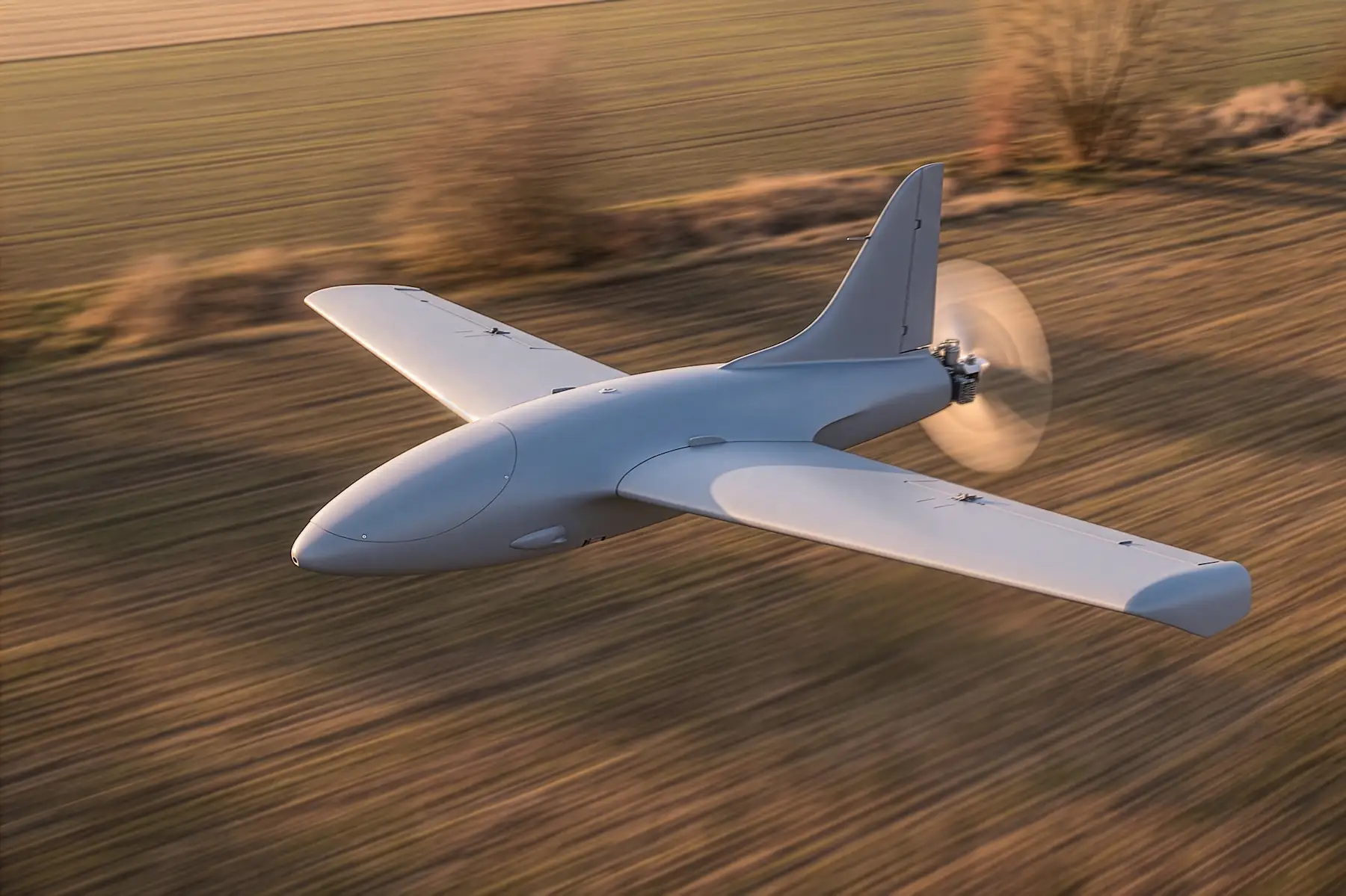 Side and front profile of the MTS fully autonomous one-way attack drone flying low over an agricultural field.